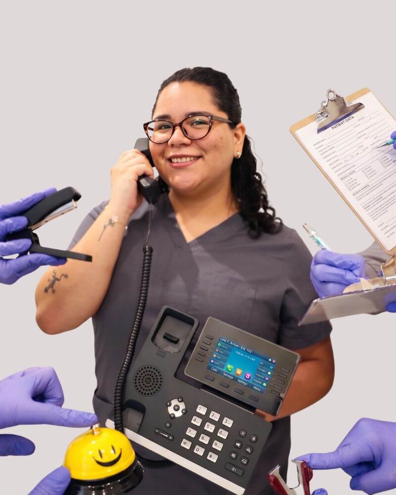 A smiling patient coordinator at Love Your Jaws Surgery Center in South Miami wearing grey scrubs and glasses, holding an office phone and surrounded by gloved hands holding administrative supplies.