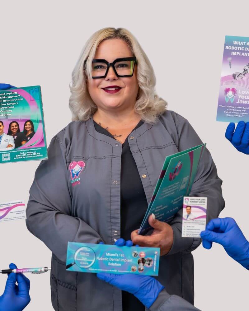 A smiling Miami general manager for Love Your Jaws, in grey scrubs and black glasses, holding a robotic dental implant brochure. She is surrounded by hands in blue gloves presenting information on advanced solutions like arch reconstruction, extractions, and jaw surgery.